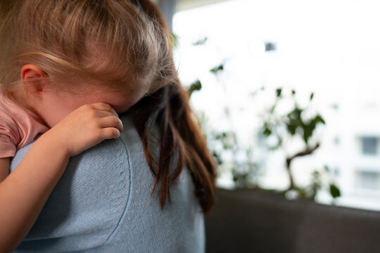 Child hiding face while mother comforts her
