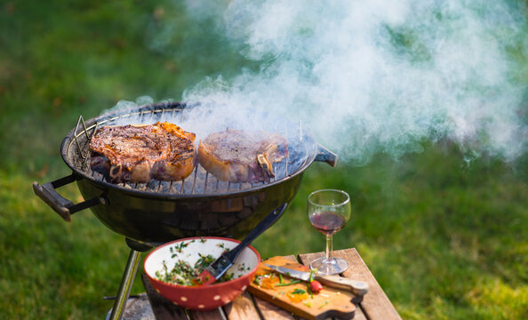 Grilling steaks outdoors in a backyard