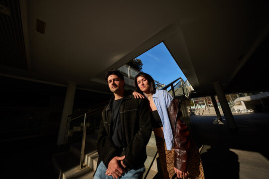 Two people standing under a building with clear blue sky above