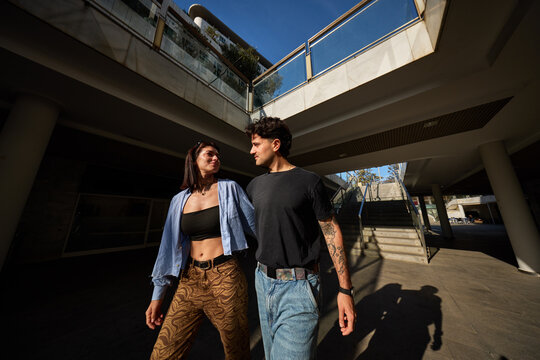 Couple walks together at modern building during bright day