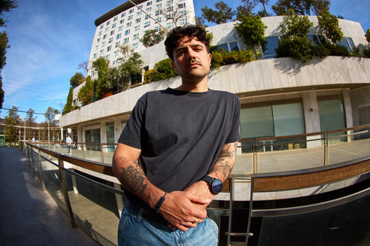 Young man stands by modern building in city during daytime