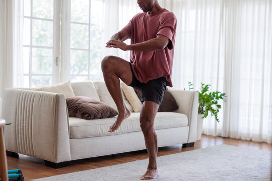 Man doing knee raises in a bright living room.
