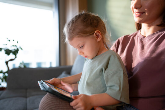 Child uses tablet while sitting on a lap