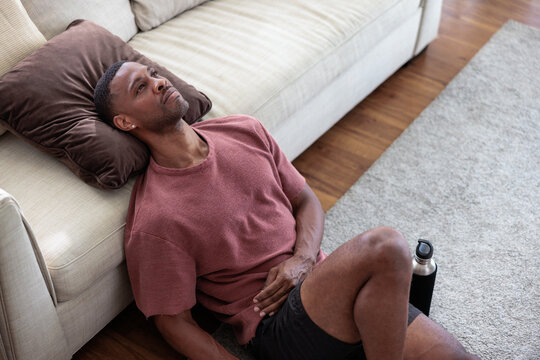 Man resting on floor after workout with water bottle at home
