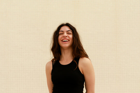 Woman Smiles While Standing Against a  Wall