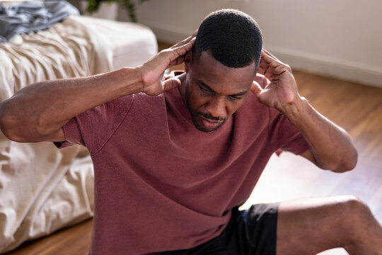 Man doing sit-ups on floor in bedroom.
