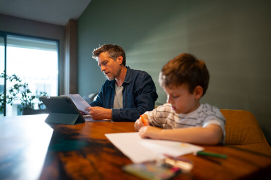 Child drawing while father works in background