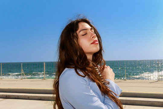 Young Woman Enjoys Sunlight by the Seaside 