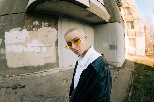 Young Person Poses Outside a Building With Glasses in the Sun
