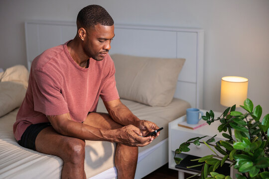 Man on bed using phone in bedroom setting.