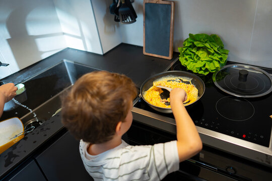 Child cooks eggs in kitchen during morning