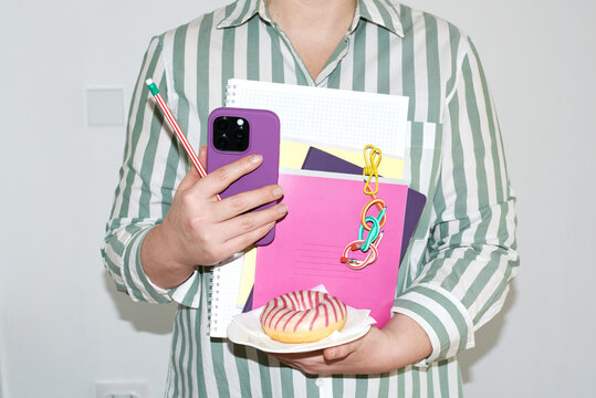 Student holds phone and notebook with snack