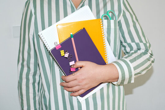A person holds notepads and stationery.