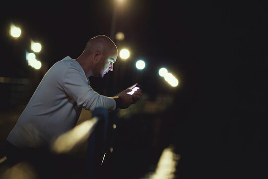 Man connecting with smartphone displaying vibrant screen at night
