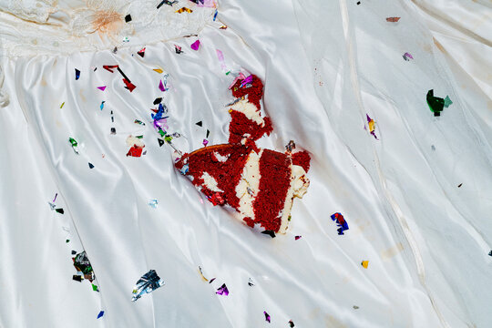 a crushed piece of cake on the lap of a bride in a white wedding dress