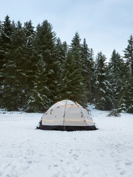 Winter camping tent glowing with festive lights in snowy forest