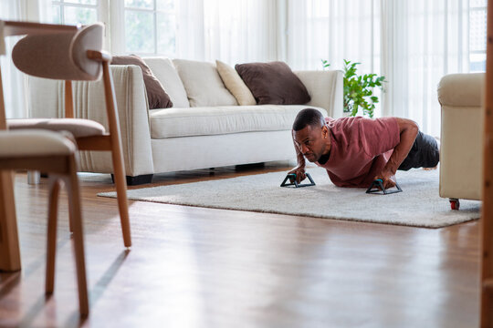 Man doing push-ups with push-up bars in living room.