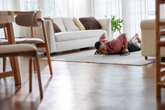 Man doing push-ups in living room, smiling.
