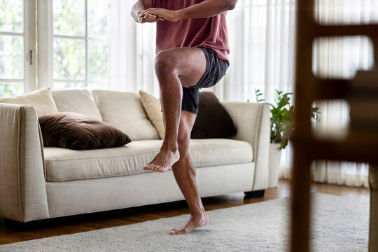Man doing high knees exercise in living room.