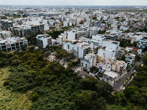 Aerial city view with buildings and tree covered land
