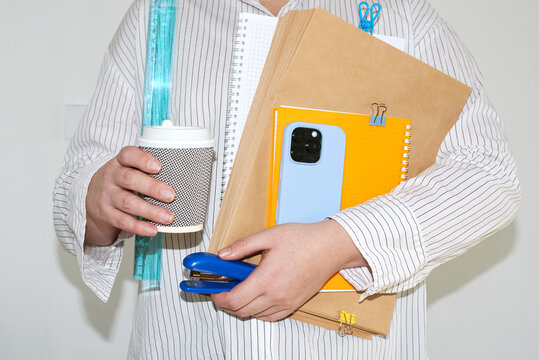 Student holds coffee and school supplies in hands