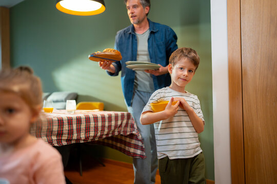 Father and Son Clearing Table After Meal
