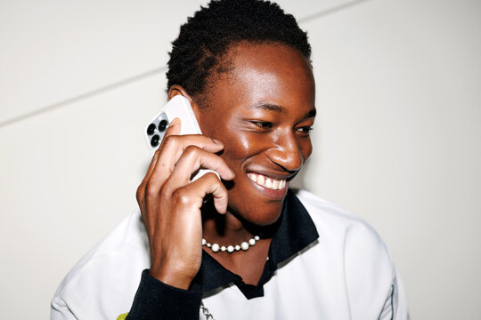 Man talking on smartphone against white wall