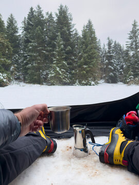 Enjoying morning coffee during winter camping in snowy forest