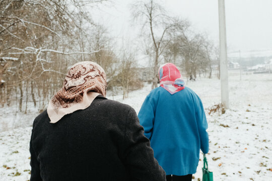 Elderly women walking through snowy village field