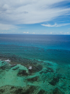 Wide ocean horizon with reef and clouded sky
