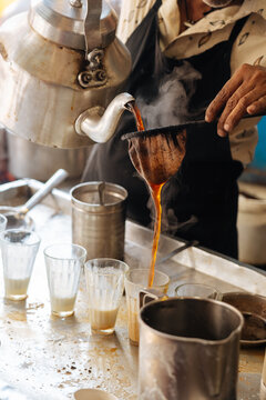 Street vendor pouring hot tea into glass cups 