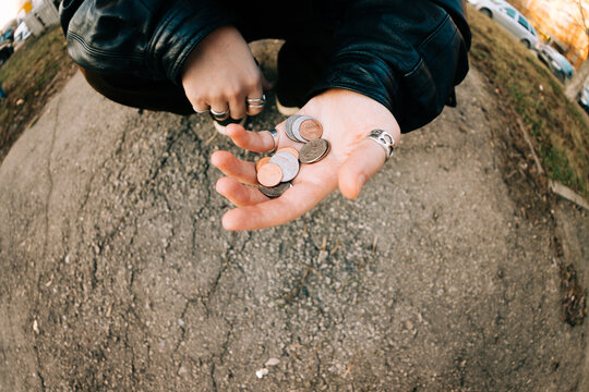 Hands Holding Coins in a Public Area During the Day