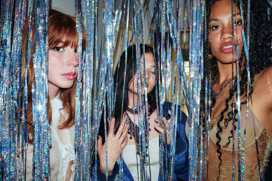 Women standing behind metallic streamers at party