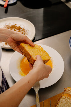Woman's hands dipping bread in egg to make Torrijas