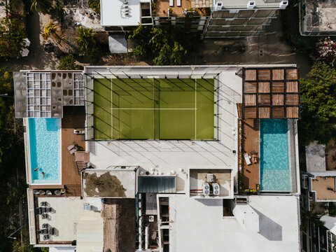 Top view of tennis court and rooftop pool in urban area
