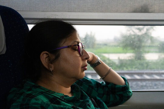 Indian woman enjoying train ride in late evening and taking a nap