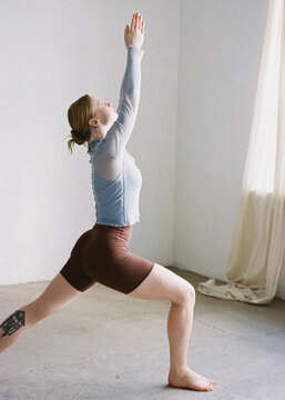 Virabhadrasana pose. Young girl in a studio practicing yoga