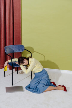 Exhausted Businesswoman Resting on Chair Next to Laptop on Floor
