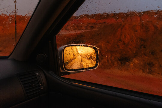 Rainy side mirror reflecting wet road