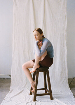 Portrait of a young girl in a studio posing on a chair
