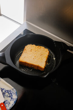 A slice of bread browning in a frying pan on an induction stove