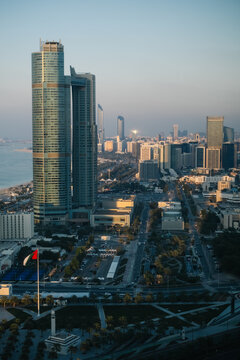 Abu Dhabi skyline with UAE flag and coastal boulevard at golden hour