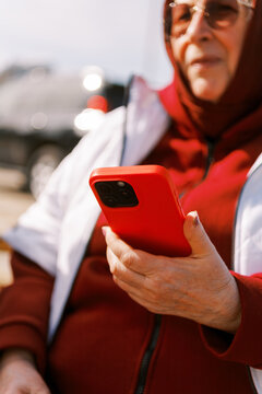 Senior Woman Using Red Phone at a Sunny Outdoor Location