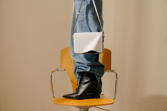 White Handbag With Black Boots On Chair