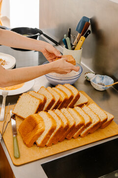 lady dipping slices of white bread in egg to make traditional Torrijas