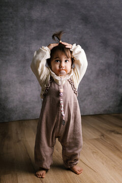 Toddler styling hair with hands holding pacifier