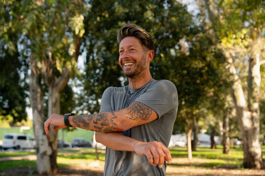 Smiling Man Stretching Arms in Park