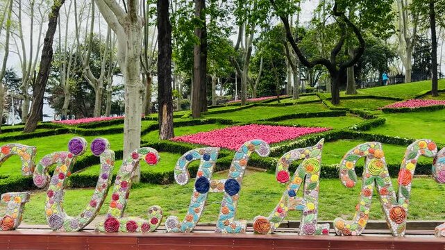 Beautiful flower lettering art on green lawn under high sycamore trees in historic Gulhane park in Istanbul, Turkey. Scenic public garden park layout, perfect for spring travel background.