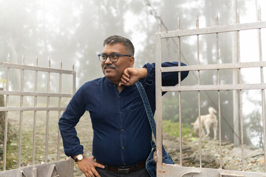 Portrait of a middle aged man standing in front of a gate in a winter