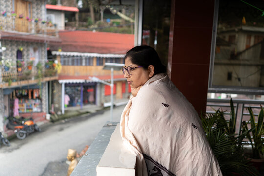 Indian woman looking outwards from the house in a mountain area